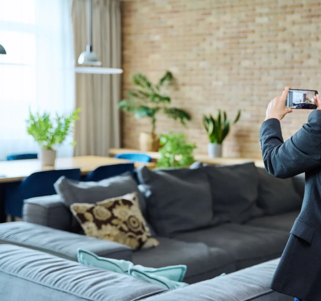 Agente che fotografa un appartamento arredato con lo smartphone